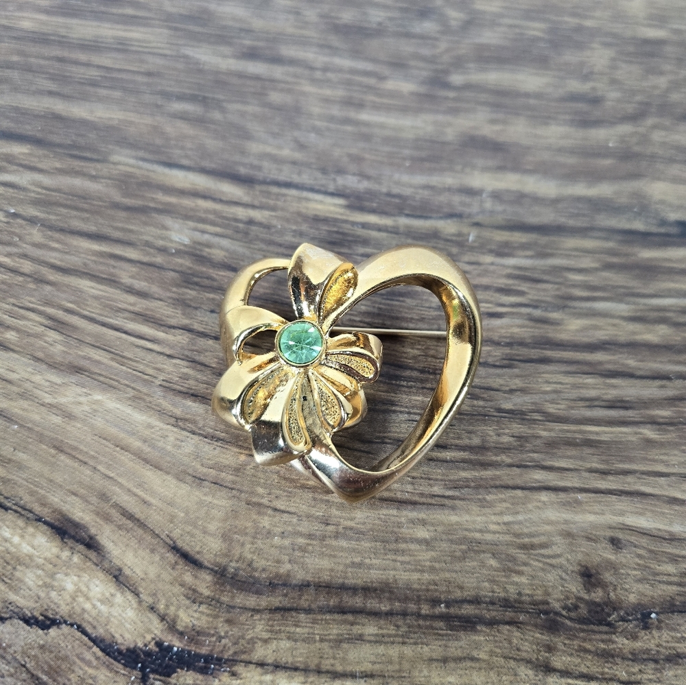 vintage Avon heart-shaped pin with a gold-tone finish and a green rhinestone